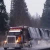 Picture of a burgundy trailer on a wet road depicting the use of 3 pc black truck tarp set.