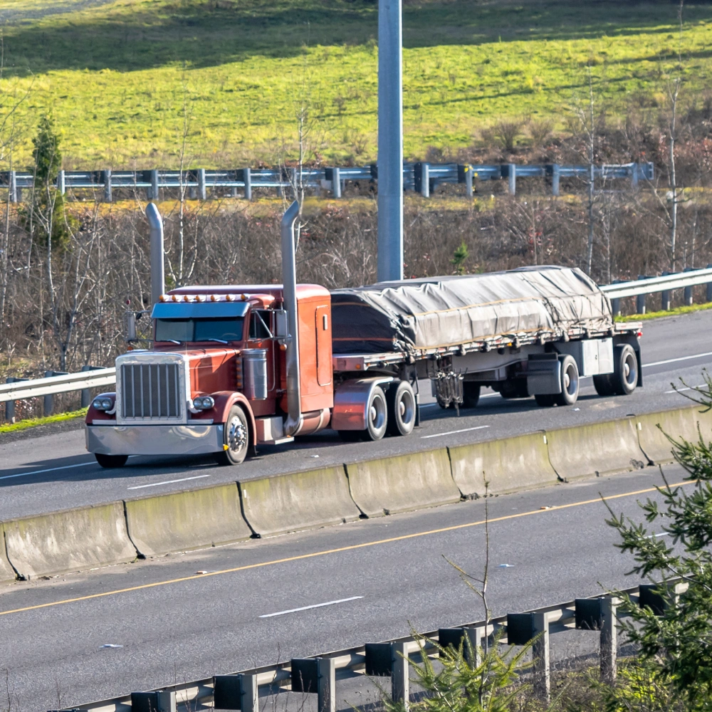 Picture of a flatbed truck carrying lumber covered with a lumber tarp showing the application of 14oz PVC coated polyester fabric