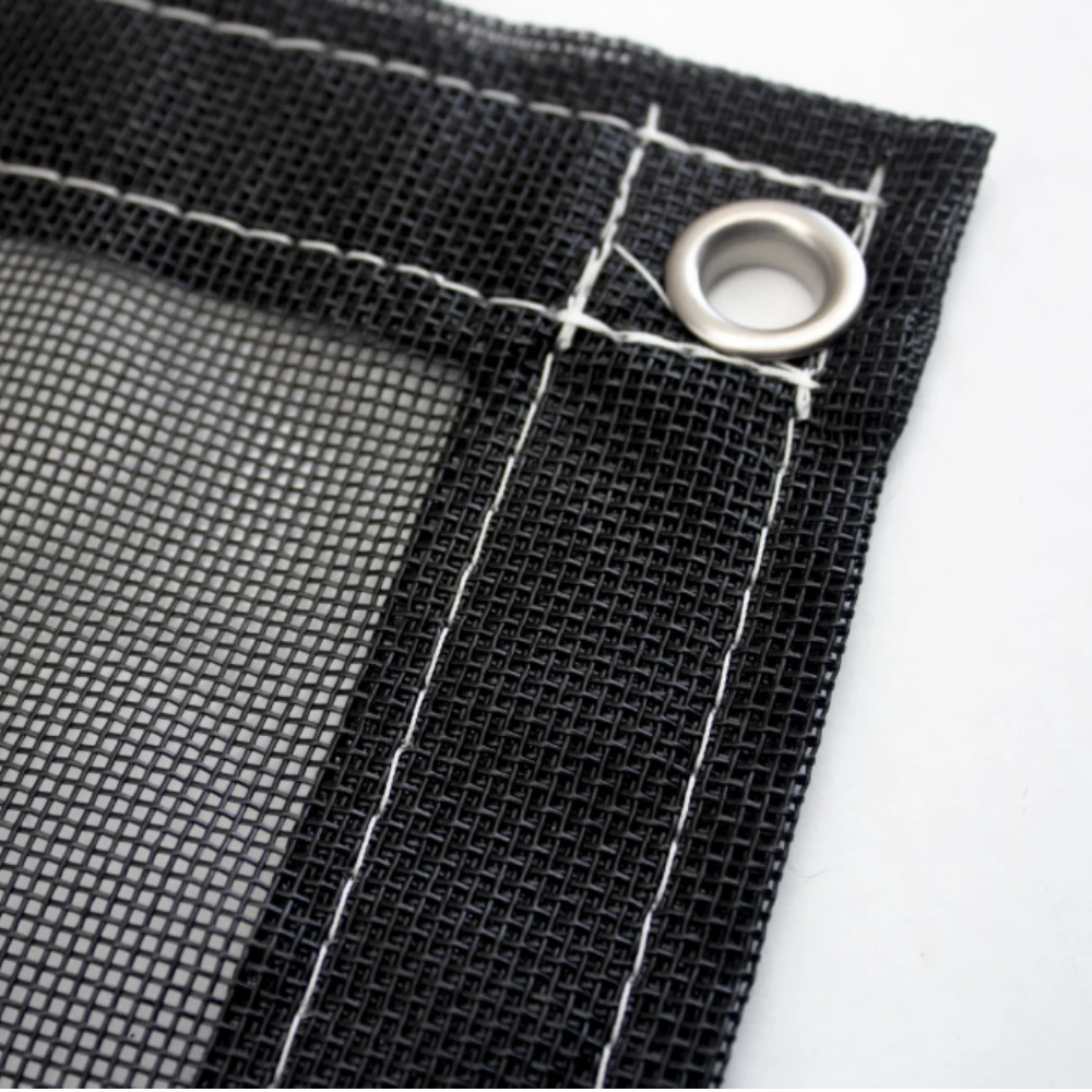 Picture of the corner of the mesh dumpt tarp focusing on the steel grommet that's strategically placed there.