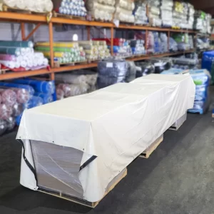 A beige multipurpose tarp covering 3 pallets in a warehouse depicting the use of an 18 oz multipurpose tarps