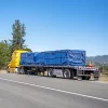 Picture of blue steel tarps covering a load on a yellow flatbed truck showing the application of 16oz PVC coated polyester fabric 20x20